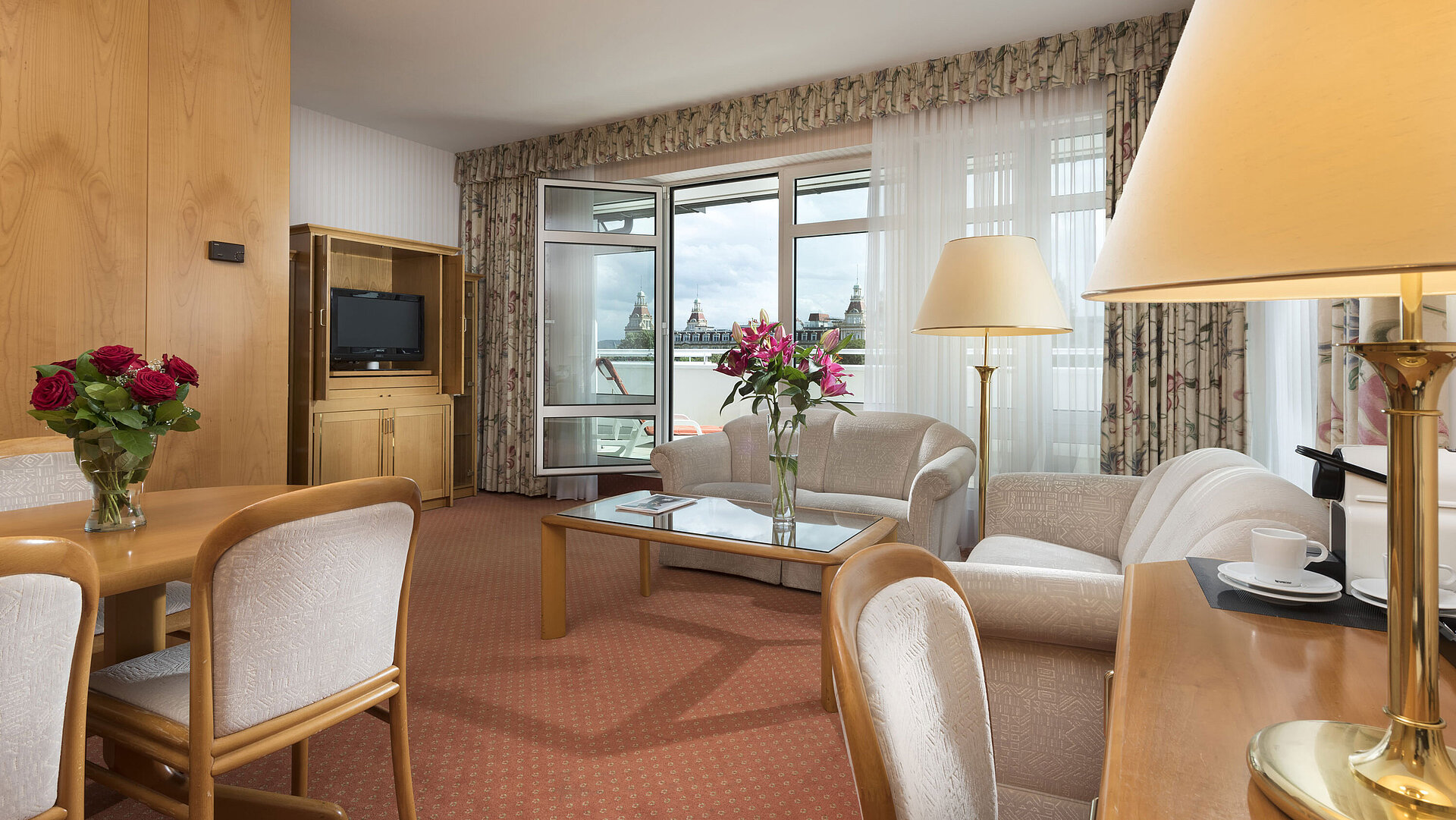 Sala espaciosa con flores, sofá, mesa y vista en el Maritim Hotel Bad Wildungen