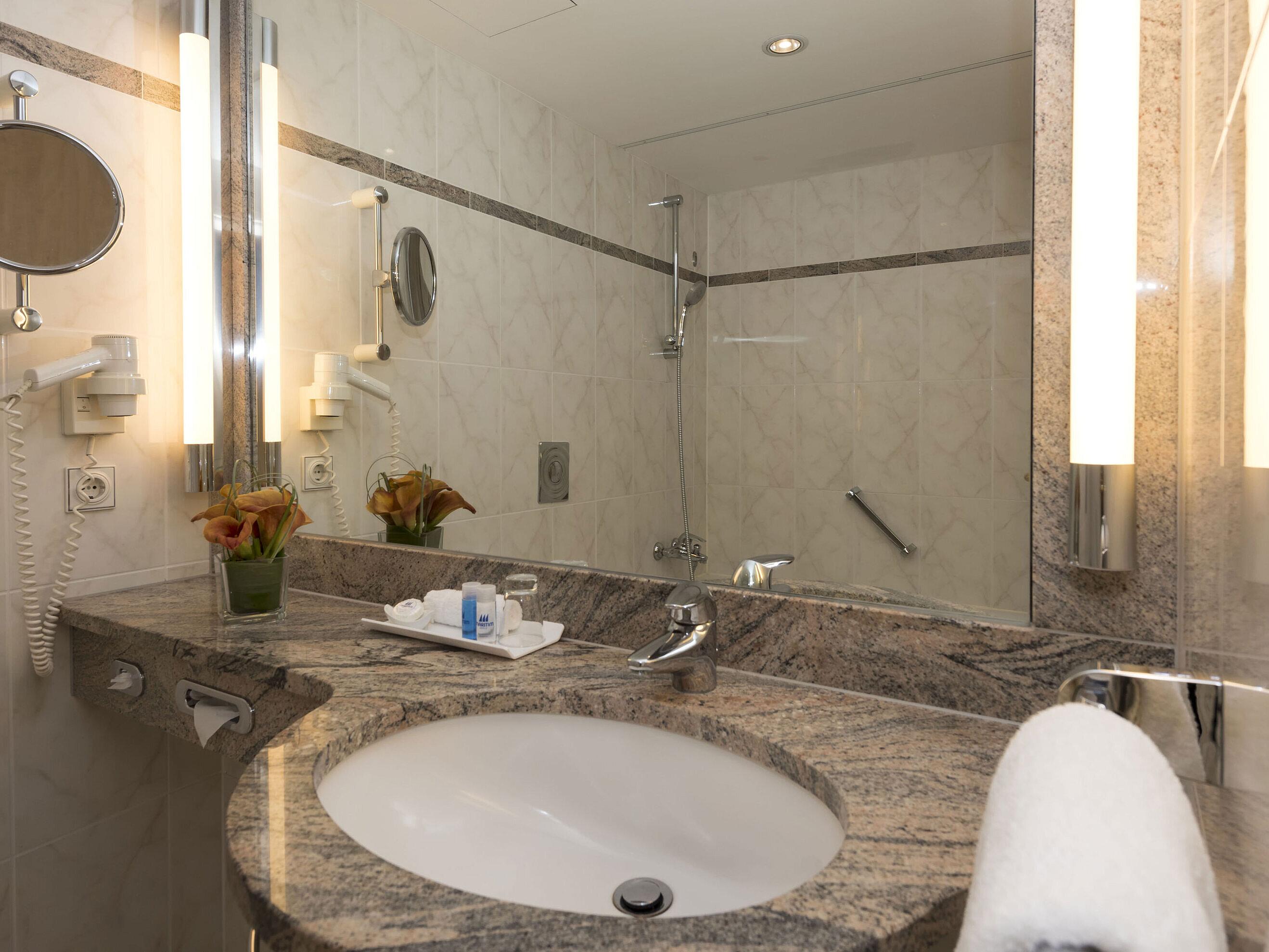 Salle de bain moderne au Maritim Seehotel Timmendorfer Strand avec lavabo en granit, miroir et douche.