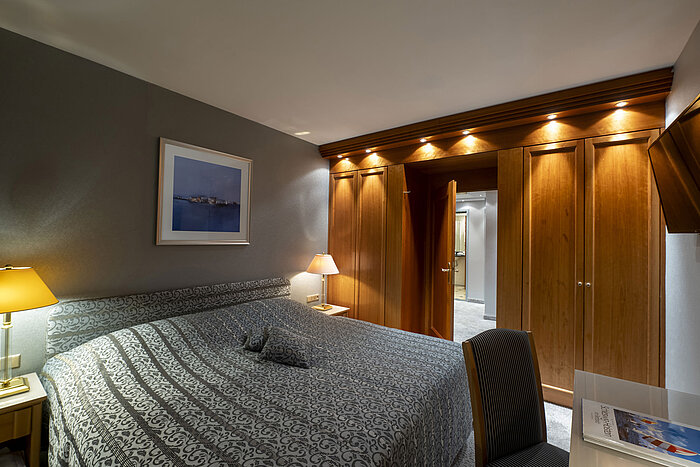 Camera della Grand Suite al Maritim Hotel Kiel con design elegante, letto grande e illuminazione raffinata.