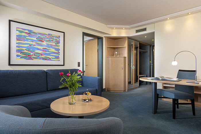 Suite moderna con sofá, escritorio y obra de arte elegante en el Hotel Maritim proArte Berlín.