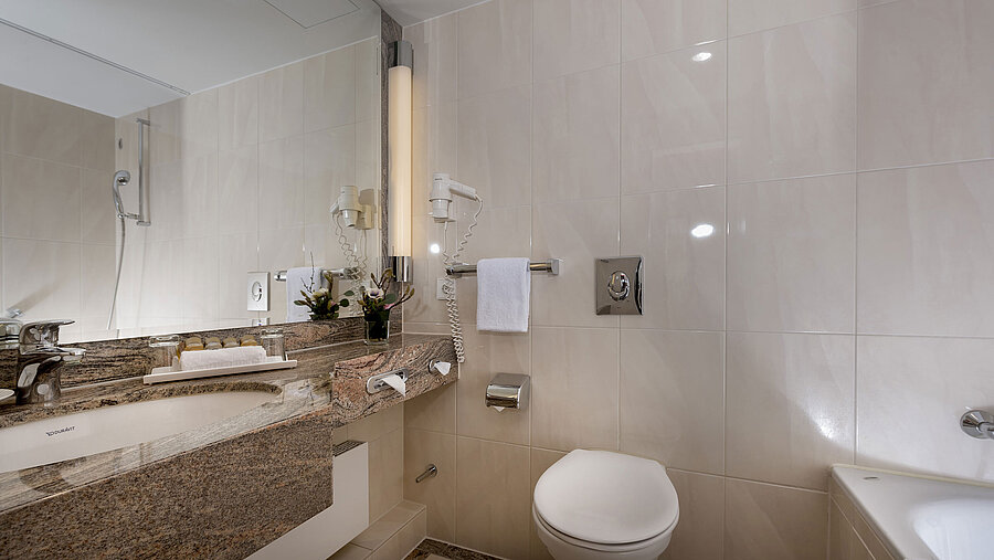 Salle de bain moderne au Maritim Seehotel Timmendorfer Strand avec lavabo, miroir, douche, WC et baignoire.