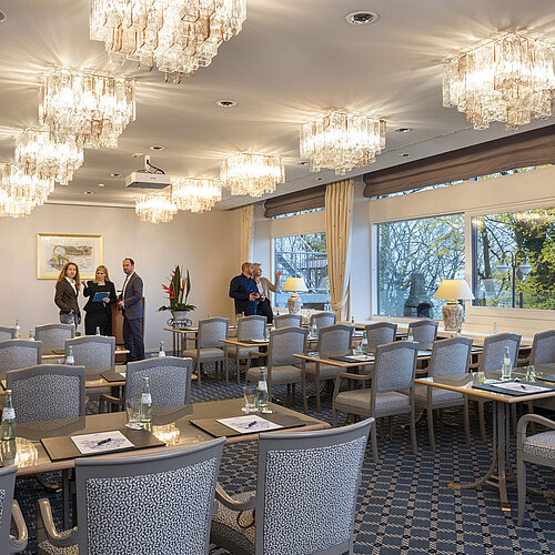 Il Salon Copenhagen del Maritim Hotel Kiel è un'elegante sala conferenze con lampadari, tavoli apparecchiati e grandi finestre.