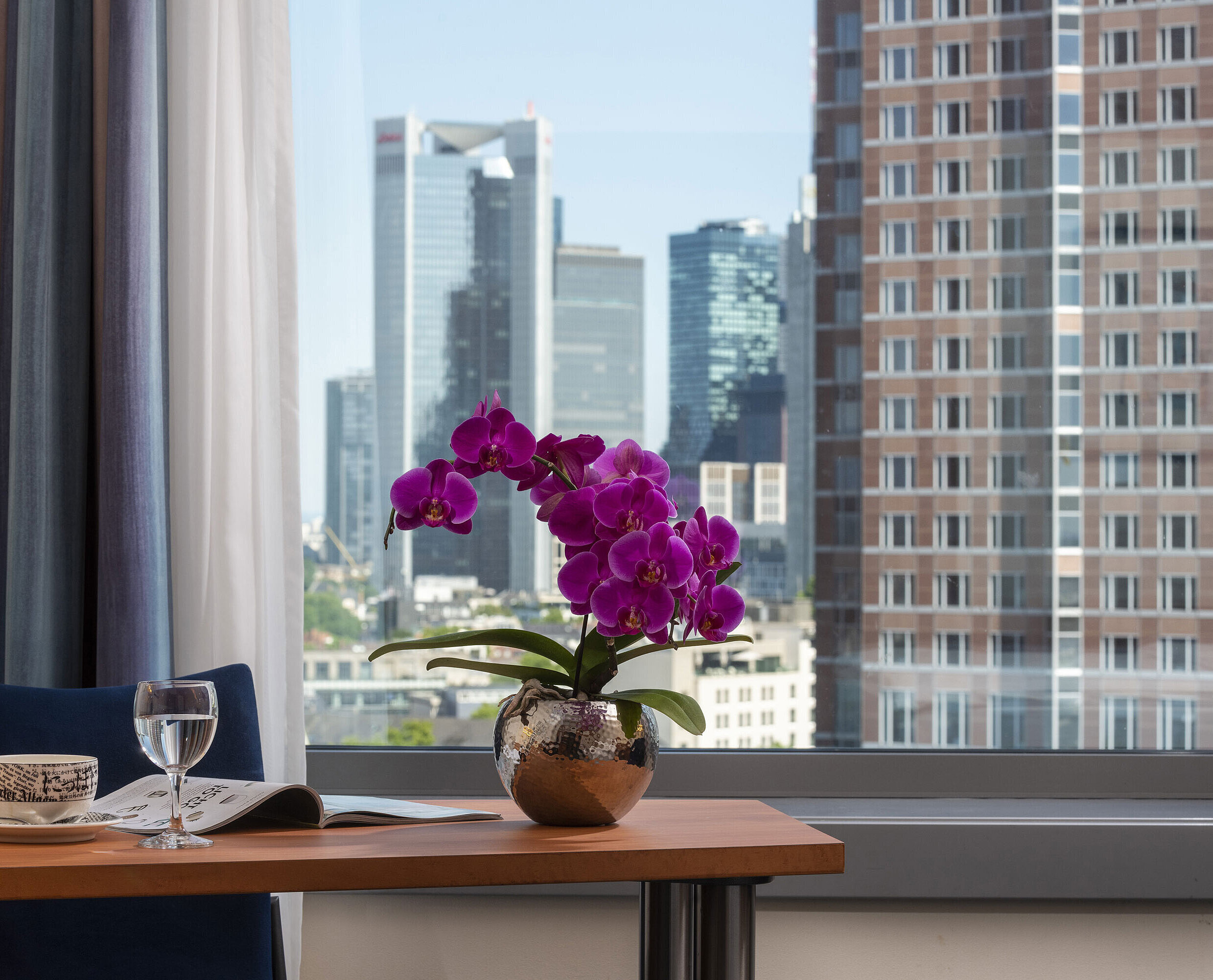 Vista dalla camera del Maritim Hotel Frankfurt con panorama skyline, scrivania e orchidea elegante.