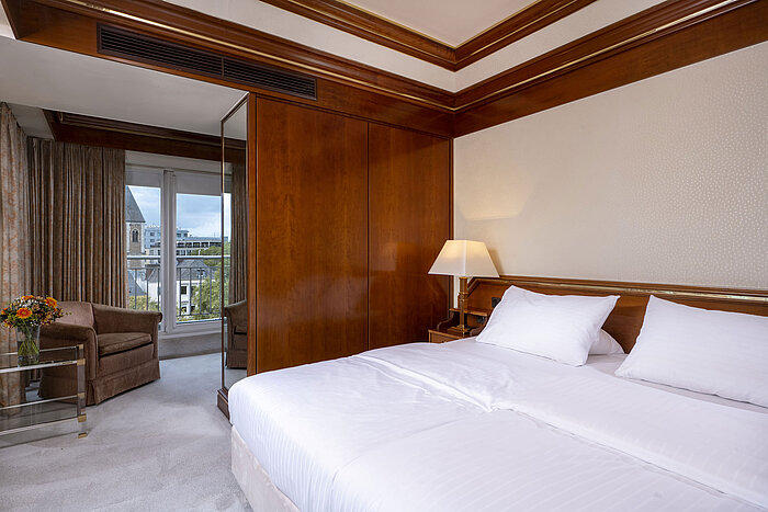 Chambre lumineuse dans la suite Heumarkt  avec un lit double confortable, accents en bois et accès au balcon.
