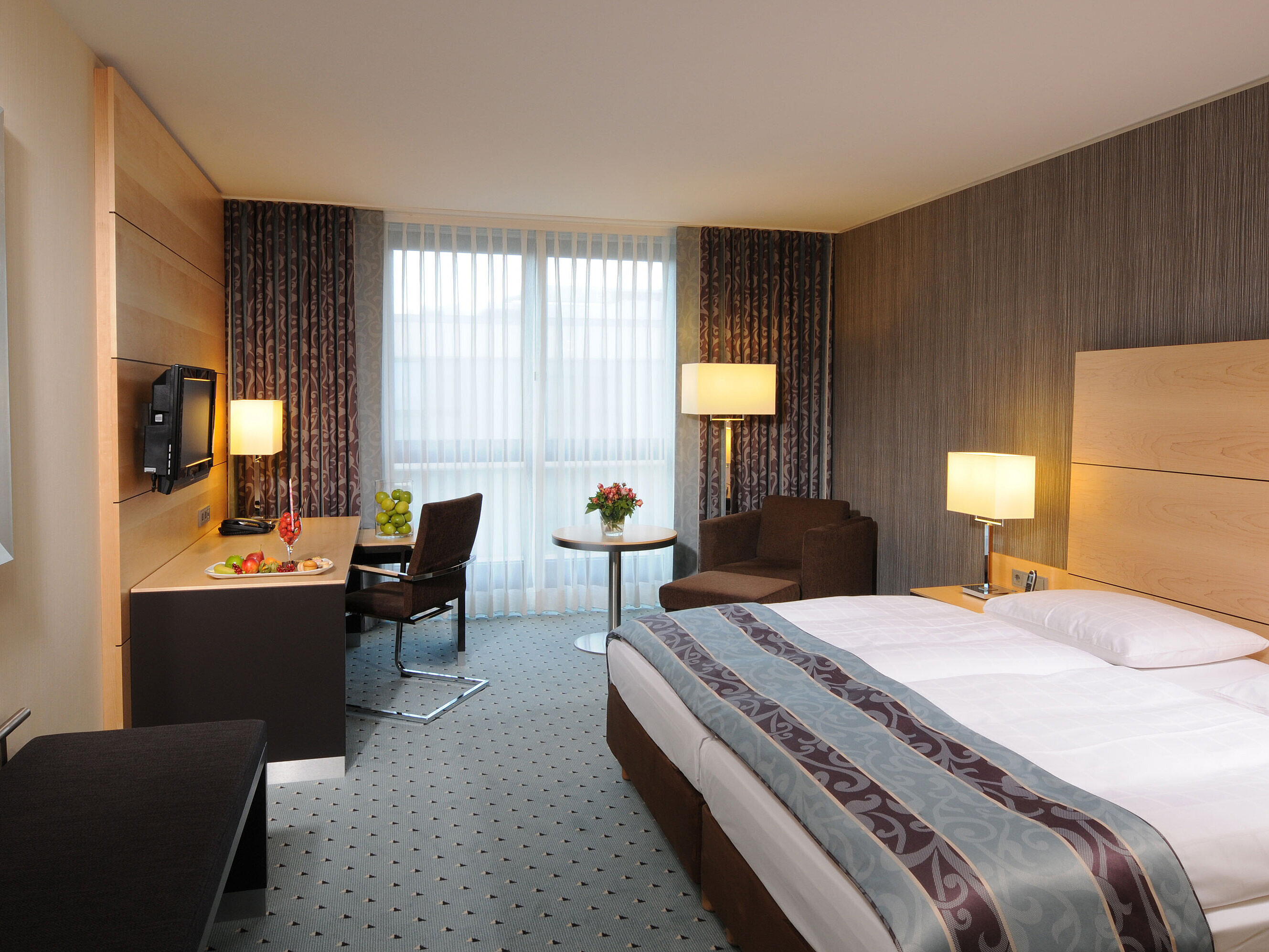 Habitación Superior en el Maritim Hotel Düsseldorf con cama doble elegante, escritorio moderno, zona de estar cómoda.