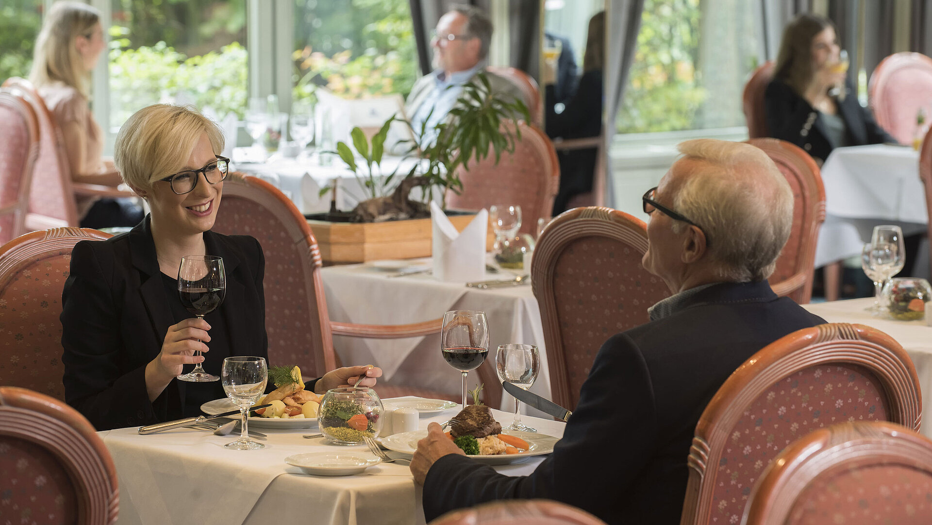 Ospiti a cena nel ristorante elegante del Maritim Hotel Bad Salzuflen con vista sul giardino