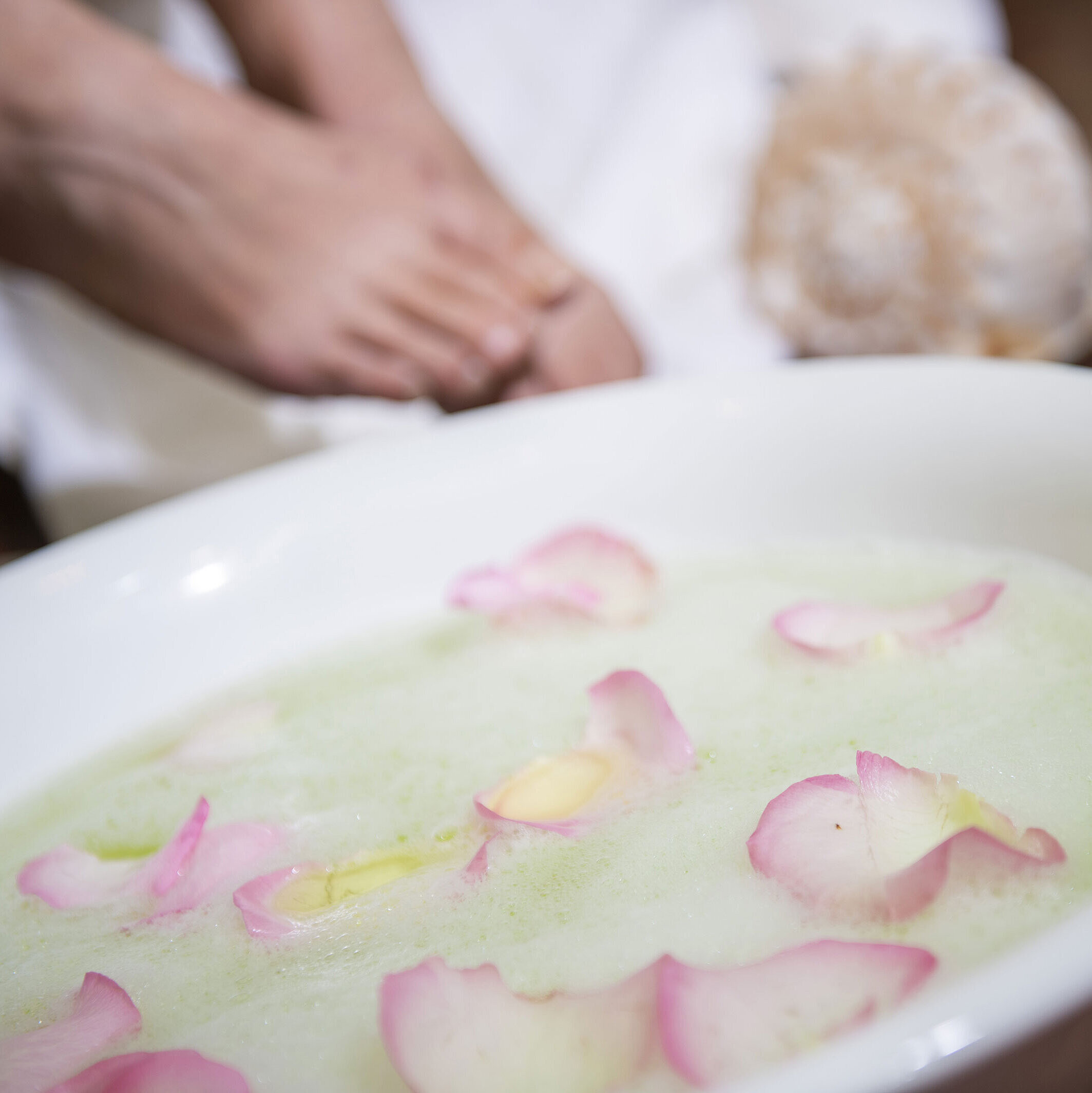 Bain de pieds avec des pétales de rose dans un bol lors d'un soin spa  pour une relaxation et des soins apaisants.